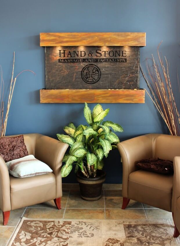 A comfortable Hand & Stone lobby decorated with plush chairs and plants.